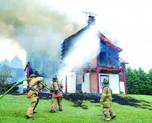 Firefighters from Buckhorn and Millville work as flames shoot from the eves of Dale and Judy Neufer's 20-year-old log home in Madison Township Saturday afternoon.