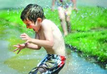 Xander Harner, 5, Berwick, runs through the stream of water from a hose his grandmother Ruthann Ridall of Berwick was holding along Vine Street in the borough Wednesday morning.