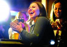 Carey Lutz, 33, of Danville, applauds as she watches herself on the TV game show "Who Wants to be a Millionaire" while sitting with friends and family at the Washies Fire Hall in Danville on Friday. 