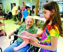 Orangeville Nursing and Rehabiliation resident Ingrid Reese, left, listens as Erika Tressler, a third-grade student at Central Columbia Elementary School, reads a book she wrote during a party at the facility Thursday afternoon.