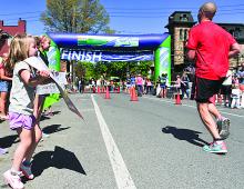 Stella Millek, left, York, cheers on her father, Mark, at right, as he near the finish line of the Rivertowns Marathon on Market Street in Danville. The marathon coincides with the annual Spring Fling street festival in Danville. 
