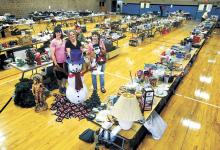 Bloomsburg YMCA members and indoor yard sale volunteers, from left, Andrea Tloczynski, Carrie Romig and Mary Clapp display a few of the items to be included in the Bloomsburg YMCA’s annual indoor yard and bake sale.