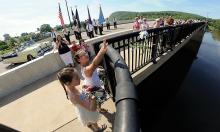 Elliona Lopez, 9, foreground left, and Abbey Lacomey, 9, throw flowers off the Danville-Riverside bridge Monday morning during the annual Memorial Day Bridge Ceremony, just before the parade through Danville.
