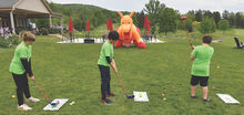 Liberty Valley Intermediate School fifth grade students, from left, Matt Styer, Noah Lee and Hunter Auman work to chip balls into the mouth of an inflatable dragon at the Frosty Valley Resort during Tuesday’s green field trip. 