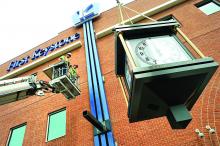 Jimmy Rymeracz and Ray Schlasselman, right, of Bartush Signs, Orwigsburg, wait for the new First Keystone Community Bank clock to be near its support beam to position themselves to help maneuver it from above Tuesday in Berwick.