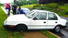 A 1993 Dodge Shadow is shown on the sidewalk along Bentley Drive in Scott Township Thursday afternoon after a crash. A Bloomsburg woman complained of pain to her head and back after crashing a car along a wet and slippery curve of Bentley Drive Thursday afternoon. 