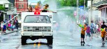 Felicia Miller, left and Kayla Derrick spray water on people from the top of a truck during the Benton Fire Parade annual water battle Saturday evening. In center in another truck is Derek Matthews.