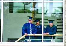 Central Columbia graduates Garrett Sanders, left, Andrew Barone and Kody Kistler look out from Mitrani Hall at BU as family and classmates arrive for commencement Saturday afternoon.
