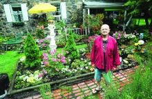 Dan Bogart shows off his flowers in front of his home Monday morning in Berwick. Neighbors of Bogart have their yard stuffed with tents and a trailer. 