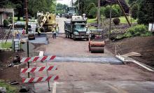 An R.C. Young, Inc. crew resurfaces over the new concrete box culvert bridge that carries Martzville Road over Glen Brook in Briar Creek Township on Wednesday.