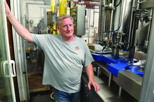 Tom Clark stands next to the bottler at the Berwick Brewing Company Monday afternoon. 