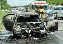 Espy firefighters break open the trunk of this Chevrolet Malibu from New York Monday afternoon. The car caught fire along Interstate 80 near the Lightstreet around 2 p.m.