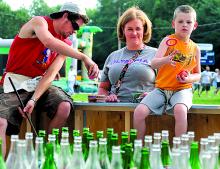 Walker Murphy, left, of Boy Scout Troop 20, hands rings to Mandy Morgan for her son Curtis Yohey, 5, to play the tossing game with at the Lightstreet Fire Company Carnival Wednesday evening. The carnival continues through Saturday.