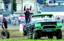 Travis Ford raises his hands in the air after climbing on his stuck truck after the vehicle landed hard and lost a rear wheel during the 4x4 Jamboree Tough Truck races Saturday at the Bloomsburg Fairgrounds.