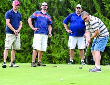 Darin Edwards, right, puts from the green as Autoneum co-workers Eric Shaner, left, Shane Temple and Mike Swartz watch during the Columbia County United Way golf tournament, held at Rolling Pines in South Centre Township Saturday.