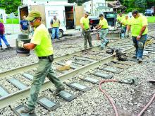 Mark Baker, left, carries a kiln away from the area where they meshed two rails together with molten steel along the North Shore Railroad line in Montour Township Monday afternoon. Finkbeiner & Associates hopes to open the crossing on Wednesday.