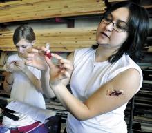 With a latex wound on her arm Bloomsburg Theatre Ensemble company stage manager A’nie Kirchner shows how to make a blood pack during the one-day Blood and Wounds Workshop to create special effects for the stage at the BTE Mitrani Building on Friday afternoon. At left is Kayti Golomb, 15, Bloomsburg. Kayti plays the Ugly Duckling in the current BTE production of the Stinky Cheese Man.