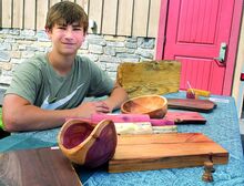 Reuben Draus, 15, displays some of his woodwork at his stand at the Bloomsburg Fair Farm Market Saturday morning. The teen's woodworking is on display at Artspace Gallery through August 15.
