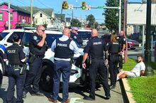 Bloomsburg police gather near Michael Fell of Berwick, seated, after stopping his Chrysler 300 on East Street in front of the former Good Old Days bar Tuesday morning. Police have charged Fell with pointing a rifle at another driver miles north on Route 11 near Lows Road.