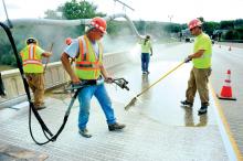 A crew from HRI, Williamsport, puts epoxy and stone on one lane of the Danville-Riverside Bridge over the Susquehanna River Monday morning. The work on the 1,440-foot-long bridge deck is expected to take about two weeks. The epoxy painting on the parapets is expected to continue when a new material is found for the sealing process.