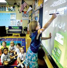 Ivy Reinhardt, a kindergarten student in teacher Tracy Knorr’s class, uses an interactive SmartBoard at Berwick’s 14th Street Elementary School on Wednesday morning, the first day of school in the Berwick Area School District. 
