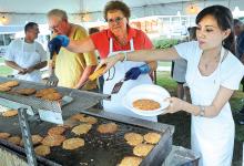 Helen Kropiewnicki, right, pulls some freshly made potato pancakes from a shelf as Pat Abraczinskas, center, and John Jessick, keep the product coming at the Our Lady of Mercy Parish Picnic in Slabtown Friday evening. 