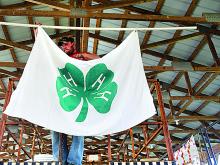 Fair volunteer Tim Tanner hangs a 4-H club banner in the market animal livestock barn at the Montour-Delong Fairgrounds Sunday in preparation for the 75th annual Montour-Delong Fair, which starts today and runs through Saturday near Washingtonville.