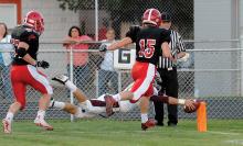 Loyalsock’s quarterback Kyle Datres dives over the goal line to score on a keeper at the end of the first quarter while being chased by Mount Carmel’s Glenn Barwicki, left, and Gabe Bogutskie during Friday night’s game at Mount Carmel.