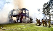 Firefighters work to extinguish the fire that consumed the house at 66 Ridge Road in Cleveland Township and several vehicles parked near the structure on Sunday afternoon. 