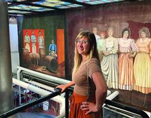 Katie Kempinski poses in front of the mural her late father, Vince Castallano, painted in the Yuengling brewery in Pottsville. She saw the finished artwork — including her father's self-portrait disguised as the seated barrel-maker — for the first time Monday.