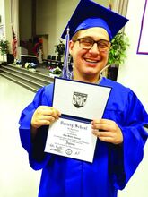 John Ebbenga smiles as he poses with his diploma after graduating from a special needs school in 2019.