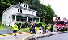 Firefighters stand outside 7974 Main Street in Mocanaqua, the left side of the unoccupied double house, after extinguishing a fire on the upper floor on Sunday afternoon. At right is the Berwick Reliance new aerial ladder truck. 
