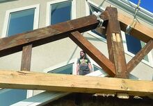 Matthew Crispell, 42, of Berwick peeks through the truss as he stands on the entryway roof at Stillwater Christian Church Friday. Church members have been hand-building a new portico since March.