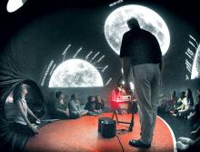 Bloomsburg University's Robert Marande, standing, uses a portable planetarium to teach a lesson on the night sky to students at Benton Middle and Senior High School on Thursday.