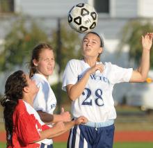 Berwick's Olivia Watkins, right, wins control of the ball and sends it over Hazleton's Kelly Flores, left, while Berwick's Mitchell Priscilla runs past during the second half of Monday afternoon's game in Berwick. 