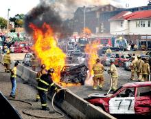 Firefighters extinguish a fire in one of the cars participating in the Bloomsburg Fair's demolition derby near the grandstand on Saturday afternoon.