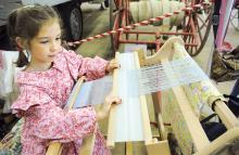 Machaella Knelly, 7, Scott Township, works on a Rigid Heddle Weaver in the Historical Exhibit Building at the Bloomsburg Fair Thursday. 