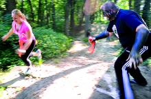 A woman runs past "Zombie" J.D. Caspersen as he tries to take runners' flags during the Zombie Run at the Test Track Park in Berwick Saturday morning. 