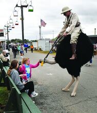 Safari Sam and Oscar the Awesome Ostrich visit with Elizabeth Beers, 7, of Bloomsburg Tuesday afternoon on the Bloomsburg Fairgrounds. 