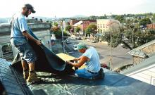 Joshua Walker, left, and Paul Mehallow work on installing a rubber base to a side roof on the third floor of the Boyd House in Danville Tuesday morning.