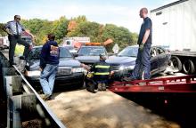 State Police Cpl. Michael Giantisco, left, stands on the guardrail by his unmarked 2008 Ford Crown Victoria and talks with Falzone’s Towing workers as they clear the four cars, including Giantisco’s cruiser, one pickup and a tractor-trailer following the accident in the eastbound lanes of Interstate 80 at Tank on Thursday.