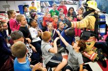 East End Fire Company Chief 61 Leslie Young, in turnout gear, wades into high-fiving third graders during a Fire Prevention Week visit to Danville’s Liberty Valley Intermediate School on Tuesday. 