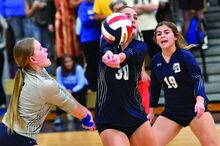 Berwick’s Cassidy Evans, center, keeps the ball in play while between Zoey Force, left, and Makayla Brown during the first game in their match against Abington Heights Monday night in Berwick. 