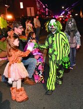Emma Woodruff, 6, gets a high five from Hunter Makuch, 8, as she stands along the Halloween parade route on East Market Street in Danville Thursday night. 
