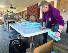 Volunteer Hunter Pugh sorts egg cartons outside the Bloomsburg Food Cupboard Tuesday as families line up for the drive-thru food distribution.
