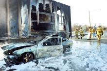 Firefighters put back the warning plates in the construction zone on Interstate 80 at the Mifflinville exit after this car got tangled up with tractor-trailer and was dragged 660 feet before it burst in to flames Monday morning in the eastbound lanes.