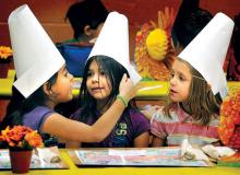Kindergarten students, from left, Isabella Soto, Maliya Keromi and Starr Anderson wear paper pilgrim hats and chat before the start of the annual Thanksgiving Feast at Northwest Area Primary School in Huntington Mills on Thursday. 
