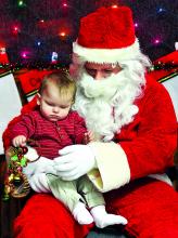 Phoenix Fowler, 10-months, shows more interest in Santa's sleigh bells than Santa