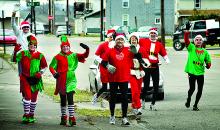Participants in the annual Christmas Eve Chimney Sweep Santa Run jog up Second Street