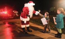 Owen Zanoline, 4, gives Santa a high five while standing with his sister Kaitlyn Zanoline, 6, in the driveway on Fourth Street in Mifflinville Monday evening. Santa is riding with the Mifflin Township Forest Rangers and Fire Company while visiting the kids in the township.
